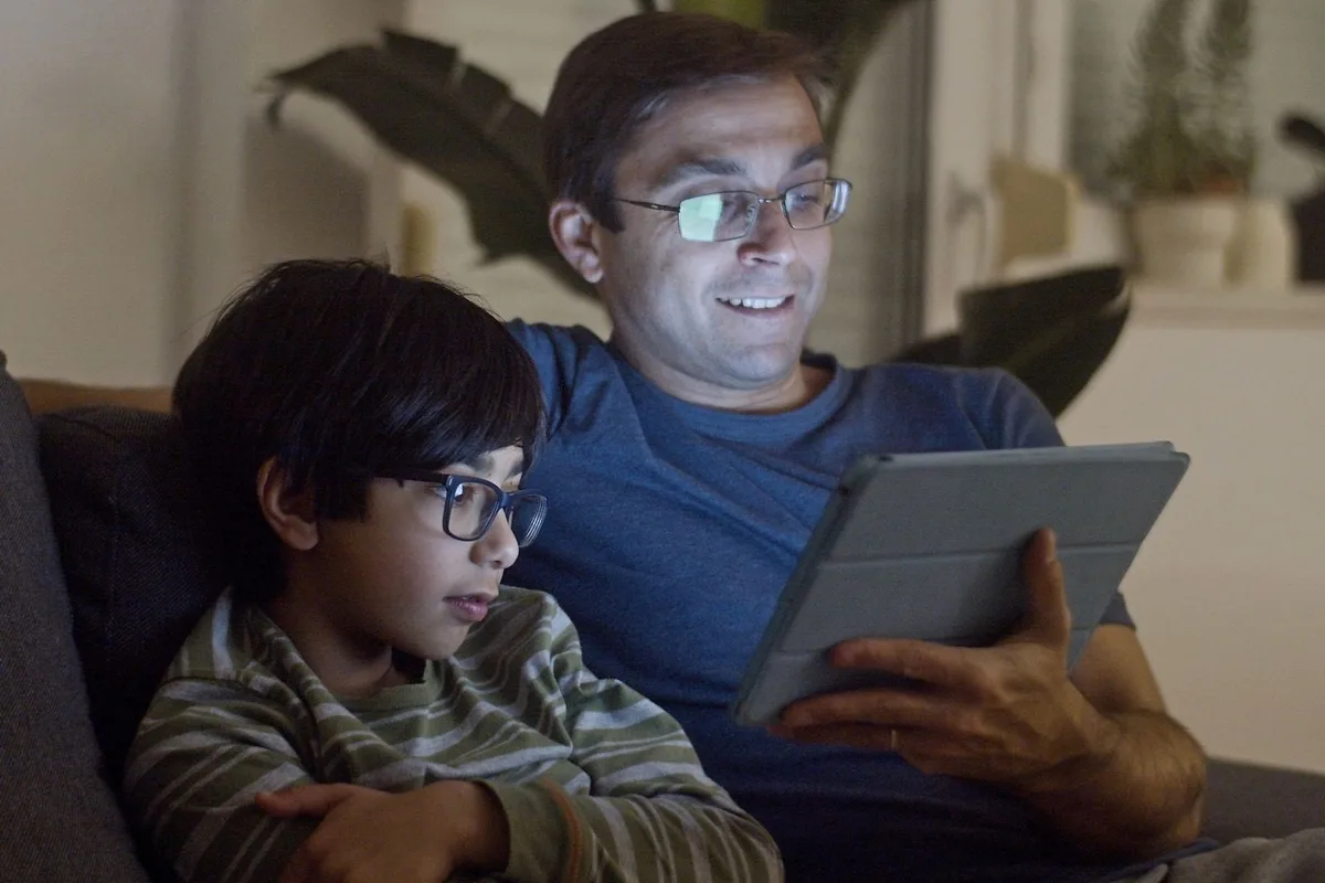 夜にタブレットで動画を見る親子。home 5Gが遅くなる時間帯