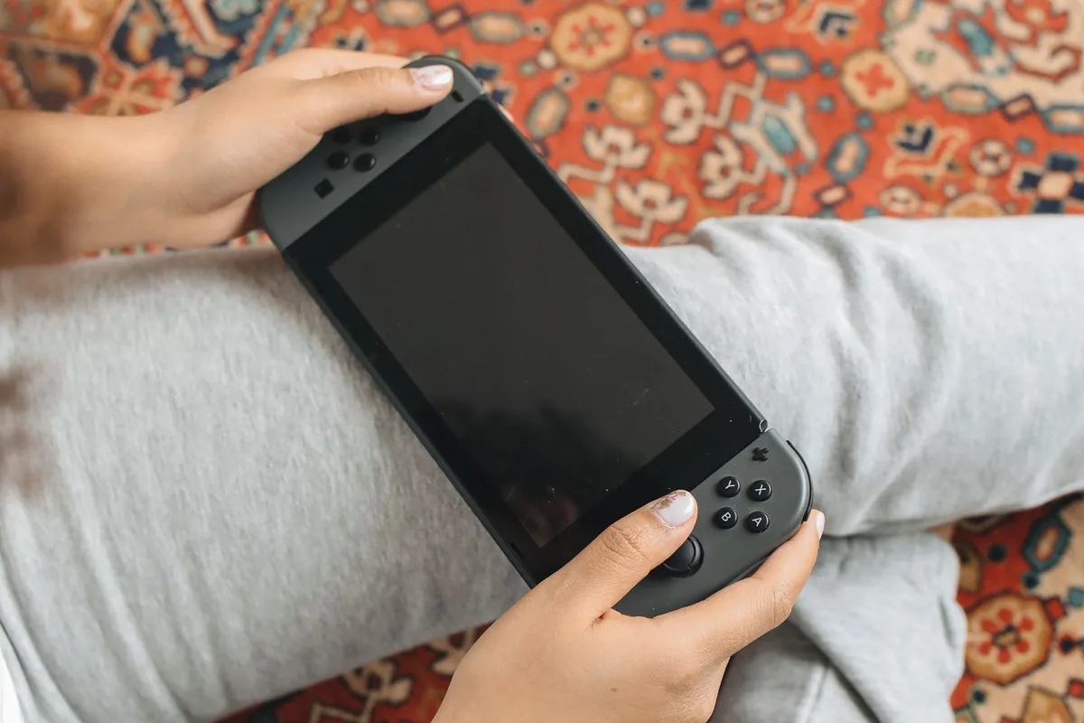 携帯モードのNintendo Switchを両手で持って遊んでいるところ