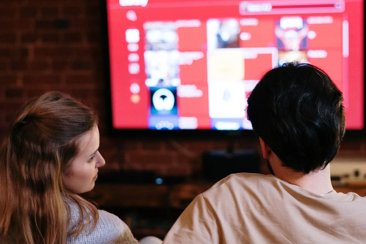 夜のリビングでソファに座り、テレビで動画を見ている二人