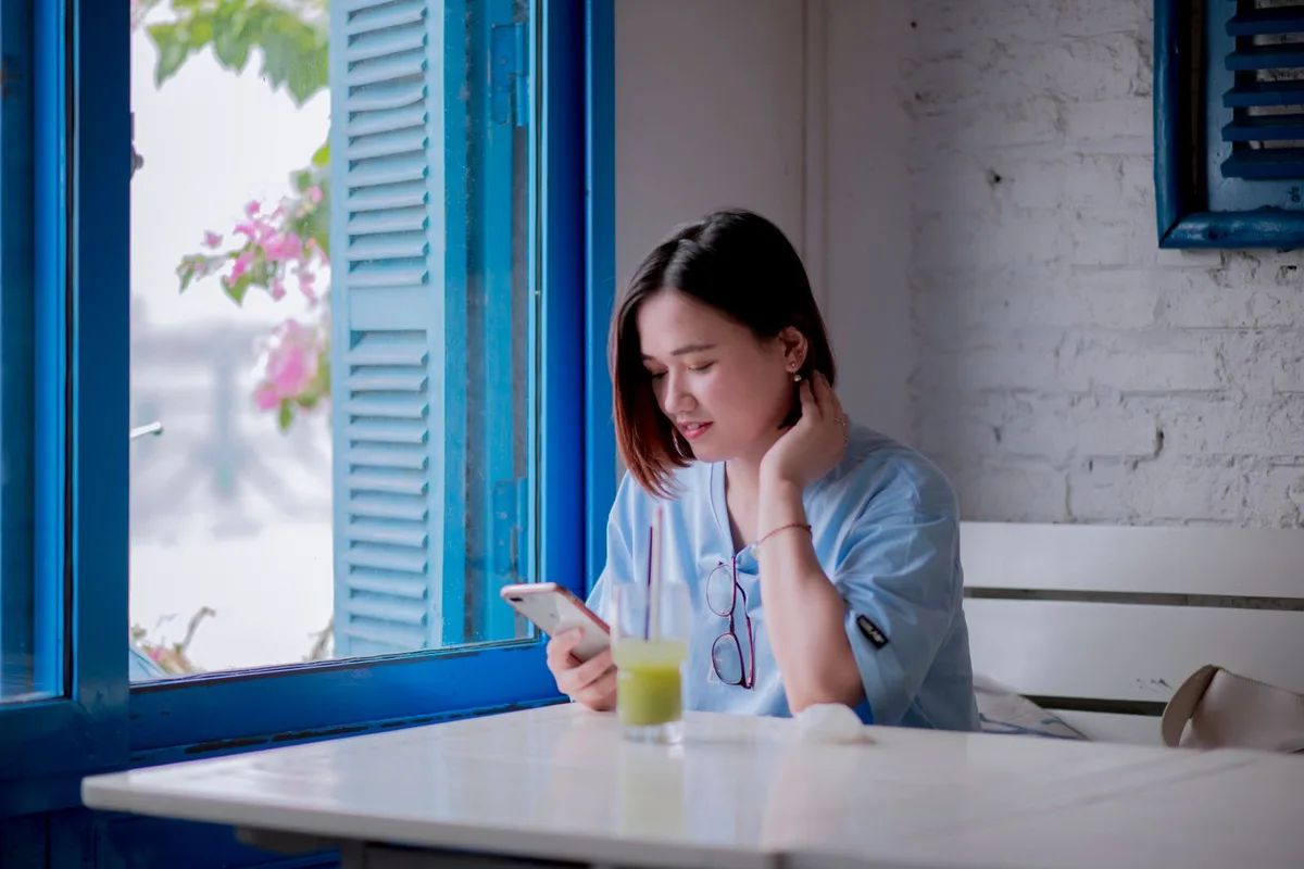 窓際でWiMAXの電波をスマホで確かめる女性